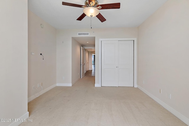 unfurnished bedroom featuring ceiling fan, light colored carpet, and a closet