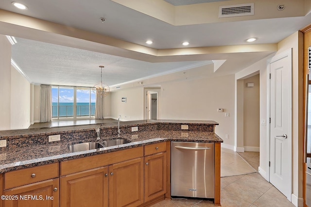 kitchen with dark stone counters, a raised ceiling, sink, a water view, and dishwasher