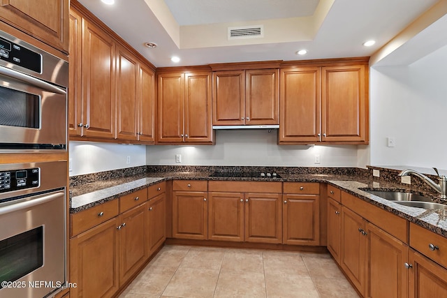 kitchen with double oven, sink, dark stone counters, and black stovetop