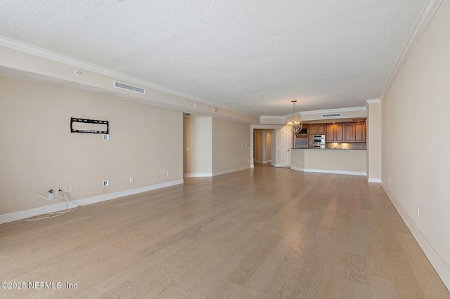 unfurnished living room featuring a textured ceiling, ornamental molding, light hardwood / wood-style flooring, and an inviting chandelier