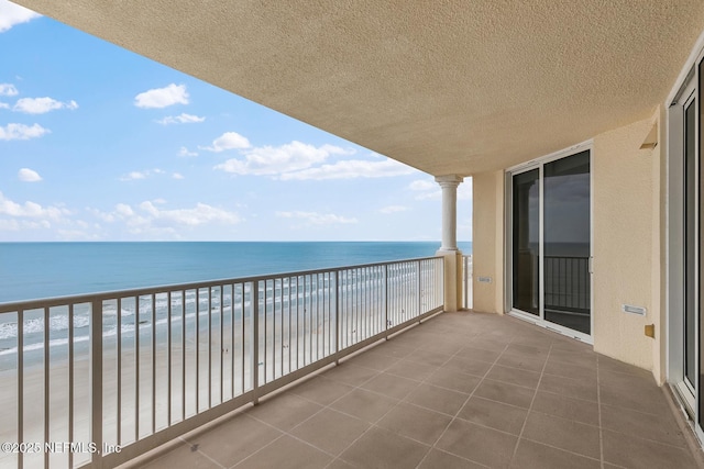 balcony with a water view and a view of the beach