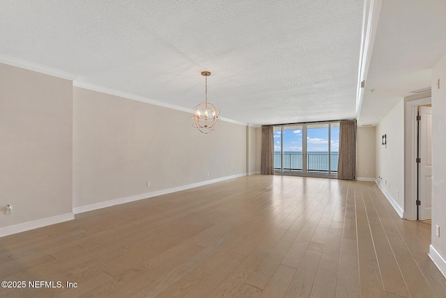 unfurnished room featuring expansive windows, a chandelier, a textured ceiling, and light hardwood / wood-style floors