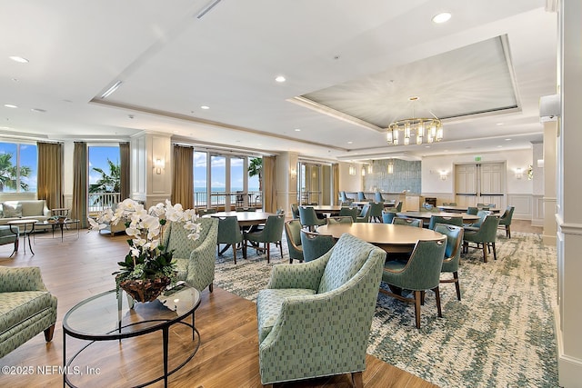 dining area featuring light wood-type flooring, a tray ceiling, and an inviting chandelier