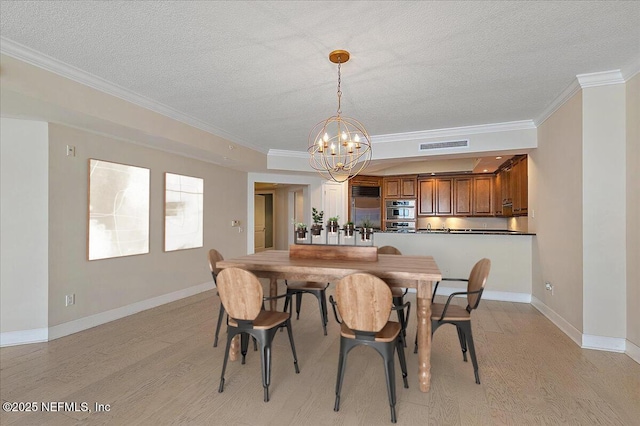 dining area with a textured ceiling, light hardwood / wood-style flooring, crown molding, and a notable chandelier