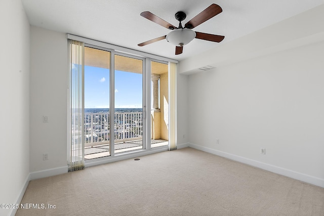 empty room featuring a ceiling fan, a wall of windows, baseboards, and carpet floors