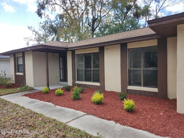 view of front of house featuring a shingled roof and stucco siding