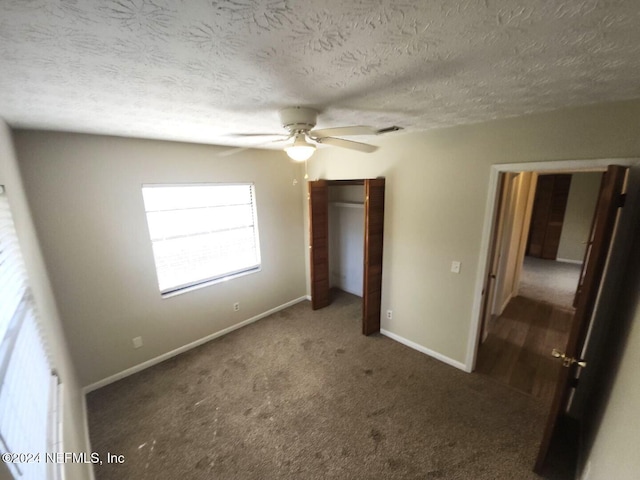 unfurnished bedroom with a textured ceiling, ceiling fan, carpet flooring, baseboards, and a closet