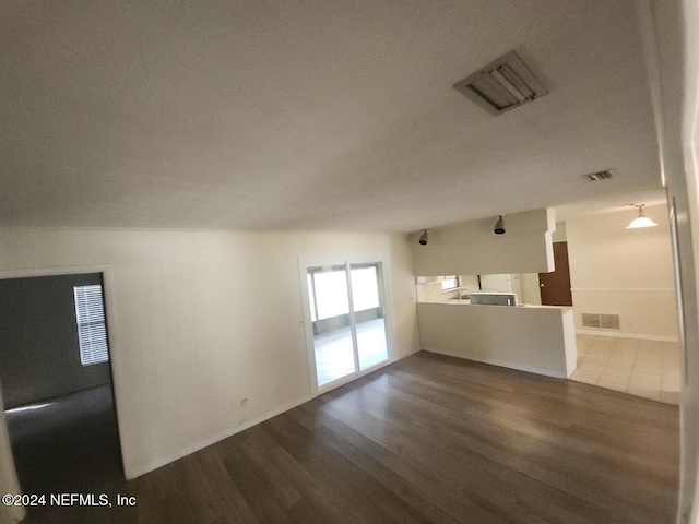 unfurnished living room featuring a textured ceiling, visible vents, and dark wood-style flooring