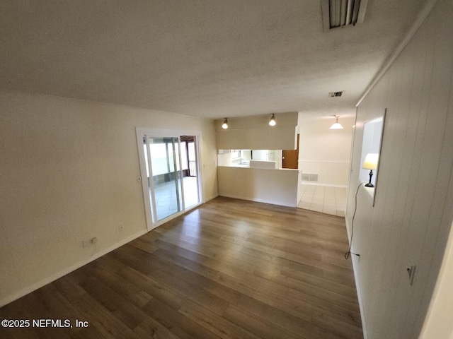 unfurnished room with a textured ceiling, visible vents, and wood finished floors