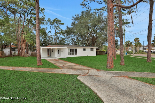 ranch-style home featuring a carport and a front lawn