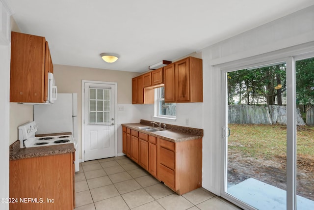 kitchen with light tile patterned floors, white appliances, and sink