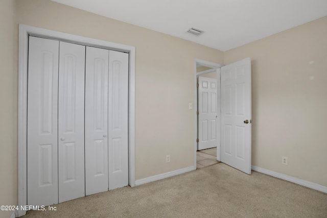 unfurnished bedroom with light carpet and a closet