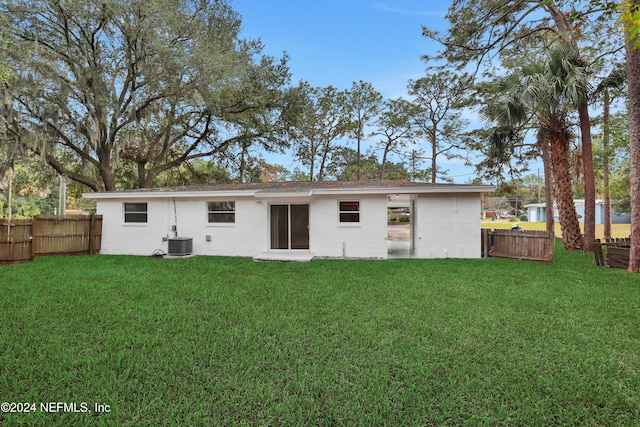 back of property with central AC and a lawn