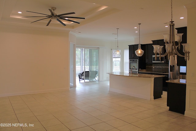 kitchen with a center island with sink, crown molding, light tile patterned floors, a tray ceiling, and decorative light fixtures