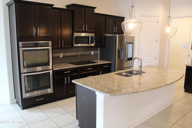 kitchen featuring pendant lighting, decorative backsplash, an island with sink, light stone counters, and stainless steel appliances