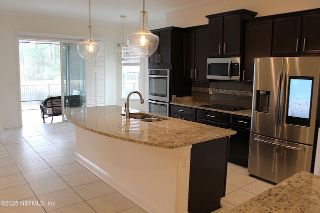 kitchen featuring a center island with sink, sink, ornamental molding, decorative light fixtures, and stainless steel appliances