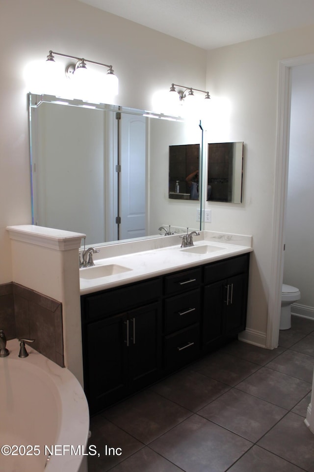 bathroom with tile patterned floors, a washtub, vanity, and toilet