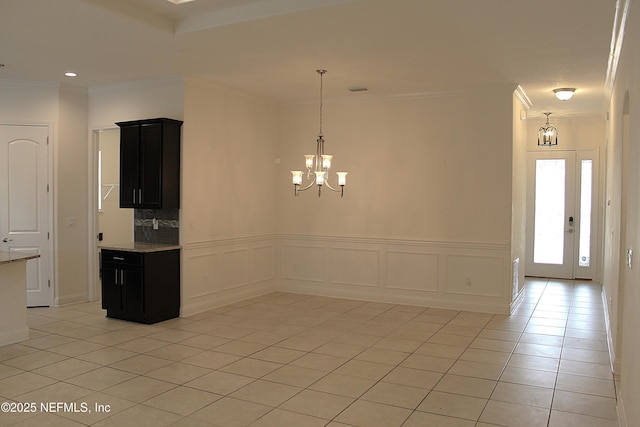 spare room with light tile patterned floors, a chandelier, and ornamental molding