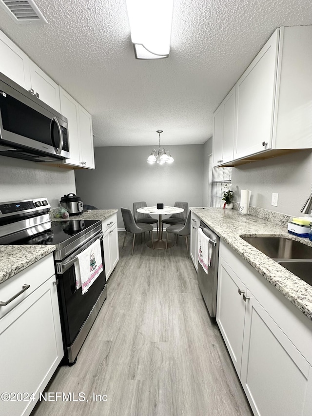 4266 Key Adam Dr, Jacksonville, FL 32218 - kitchen with appliances with stainless steel finishes, pendant lighting, white cabinetry, and a notable chandelier