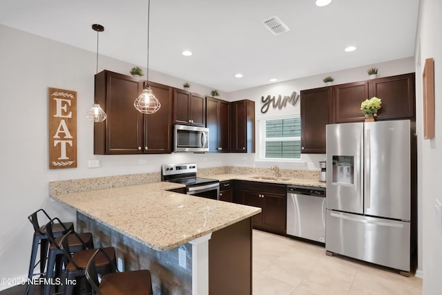 kitchen with stainless steel appliances, sink, decorative light fixtures, a kitchen bar, and kitchen peninsula