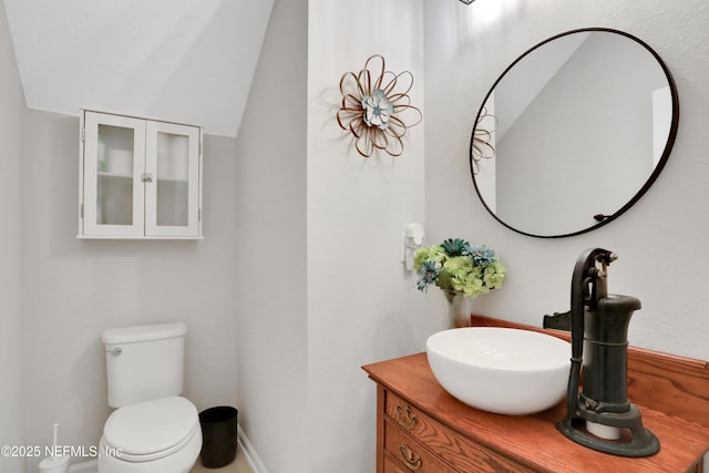 bathroom featuring toilet, lofted ceiling, and vanity