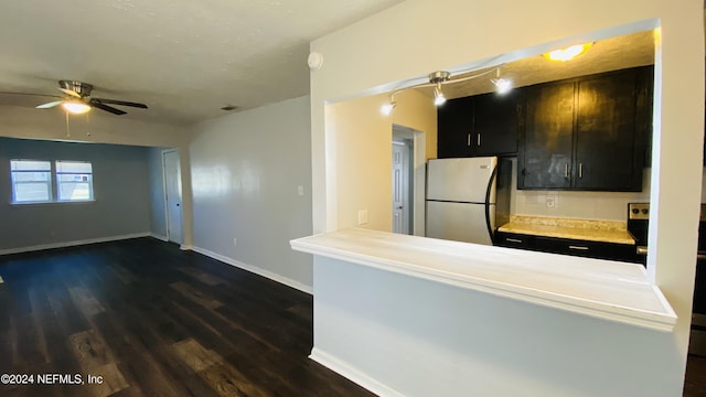 kitchen featuring ceiling fan, dark hardwood / wood-style flooring, kitchen peninsula, stainless steel fridge, and decorative backsplash