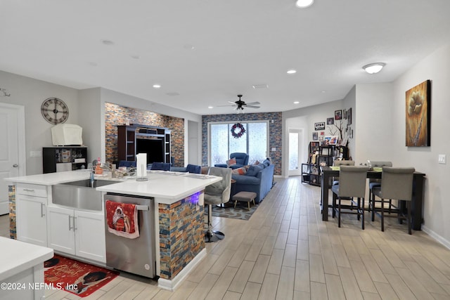 kitchen featuring a kitchen island with sink, sink, stainless steel dishwasher, ceiling fan, and white cabinetry