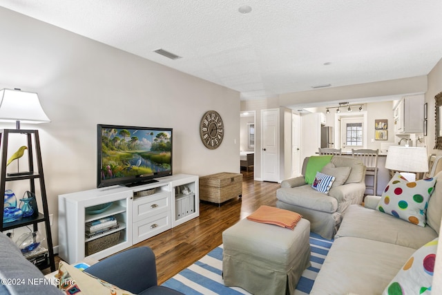 living room with a textured ceiling and dark wood-type flooring