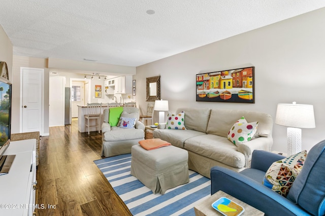 living room with a textured ceiling and dark wood-type flooring