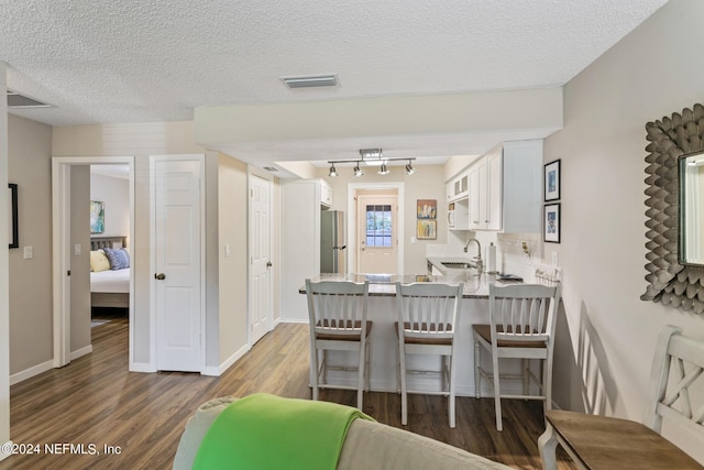 dining area featuring dark hardwood / wood-style flooring, sink, and a textured ceiling