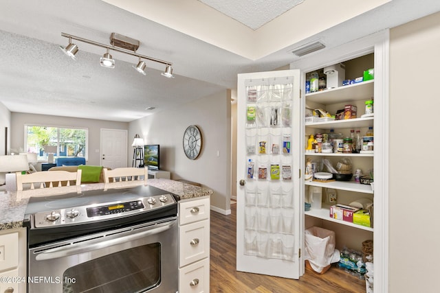 kitchen featuring light stone countertops, light wood-type flooring, a textured ceiling, stainless steel electric stove, and white cabinetry