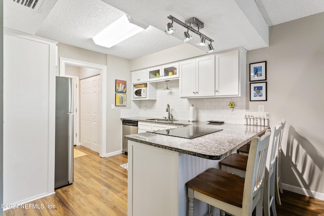 kitchen with white cabinetry, sink, a kitchen breakfast bar, kitchen peninsula, and appliances with stainless steel finishes