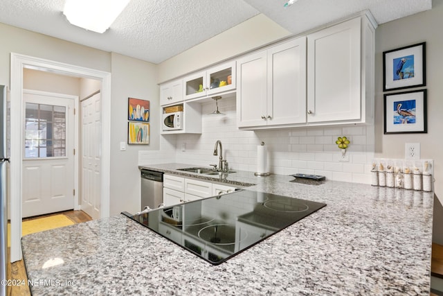 kitchen featuring dishwasher, light stone countertops, white cabinetry, and sink