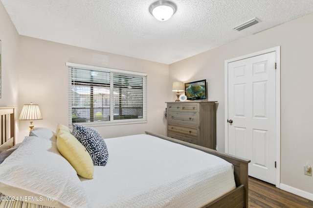 bedroom with dark hardwood / wood-style flooring and a textured ceiling