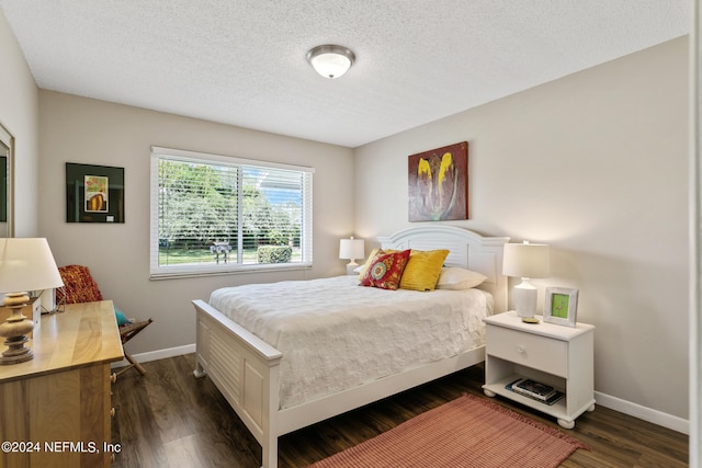 bedroom with a textured ceiling and dark hardwood / wood-style floors