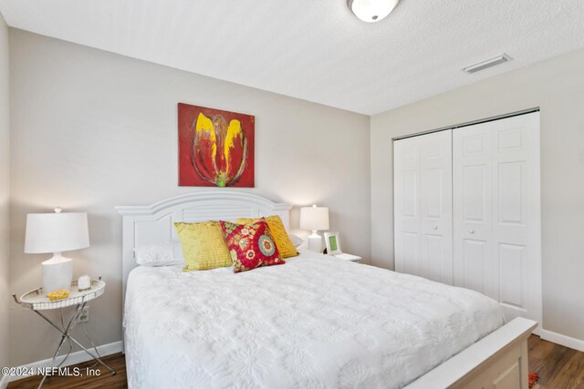 bedroom with dark hardwood / wood-style flooring, a closet, and a textured ceiling