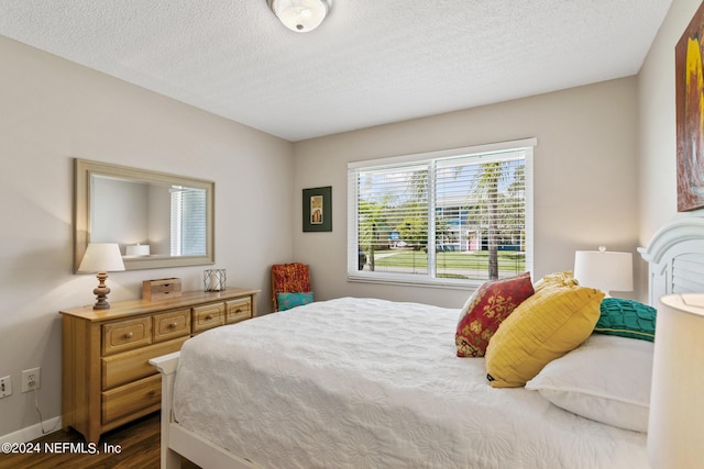 bedroom with a textured ceiling and dark hardwood / wood-style floors