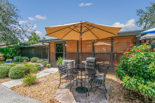 view of patio / terrace featuring grilling area, cooling unit, and a sunroom