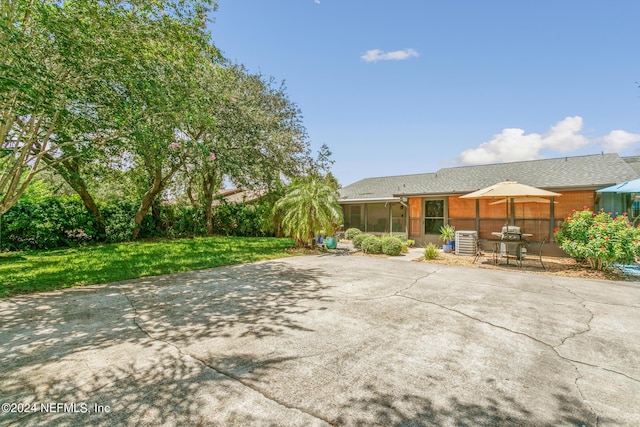 back of house with a yard, a patio, and a sunroom