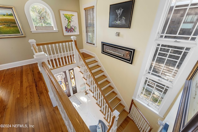 staircase with wood-type flooring and a high ceiling