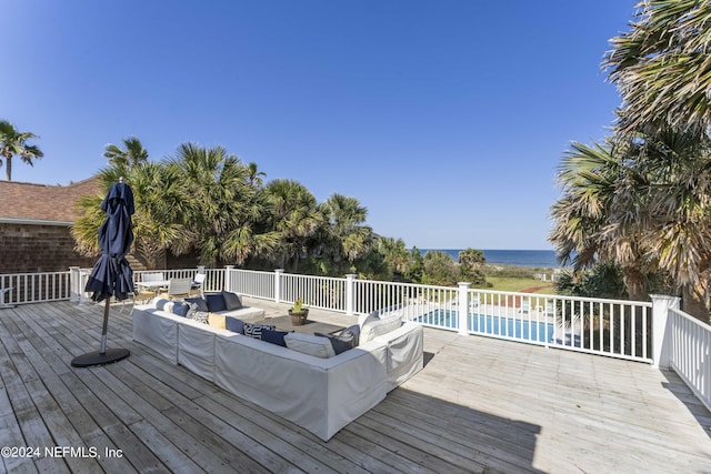 wooden deck featuring a water view, an outdoor hangout area, and a fenced in pool