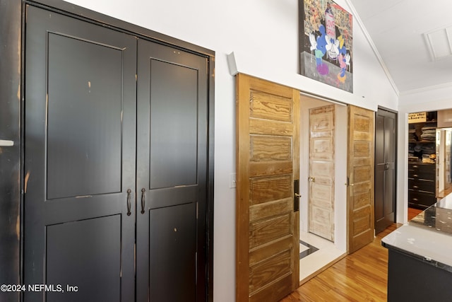 interior space with light wood-type flooring, lofted ceiling, and ornamental molding