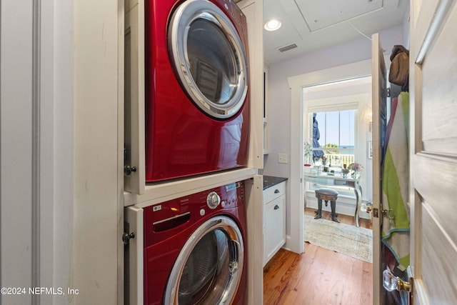 laundry area with light hardwood / wood-style floors and stacked washer and dryer