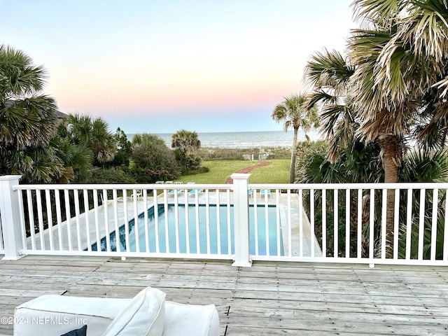 deck at dusk featuring a water view