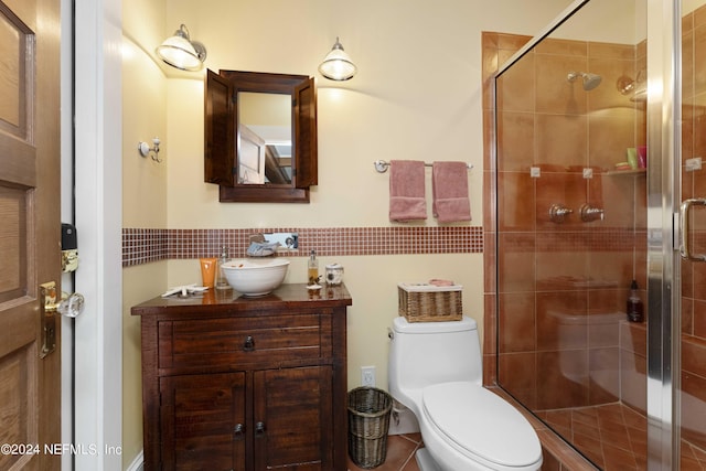 bathroom with tile patterned flooring, vanity, a shower with shower door, and toilet