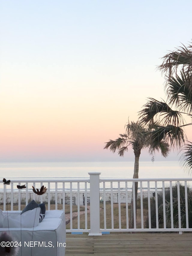 deck at dusk featuring a water view