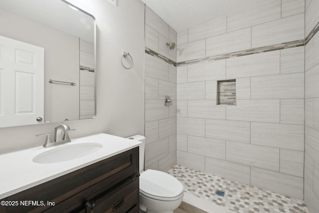 bathroom featuring tiled shower, vanity, and toilet