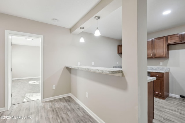 kitchen featuring kitchen peninsula, decorative light fixtures, and light hardwood / wood-style flooring