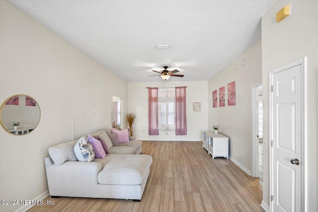 living room with ceiling fan, light hardwood / wood-style floors, and a textured ceiling