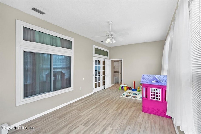 recreation room featuring a textured ceiling, light hardwood / wood-style floors, and ceiling fan